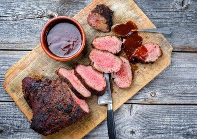 wagyu tri tip steak on cutting board with bbq sauce